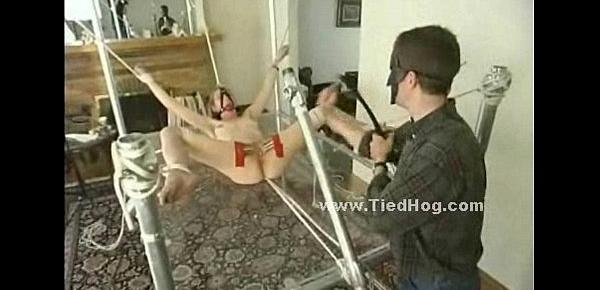  Blonde girl has her nipples bound in clamps while being tied up on a glass table